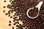 Close Up Of Coffee Beans In White Spoon On Wooden Background Stock Photo