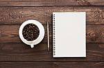 Coffee Beans In Cup And Book Blank Page On Wood Table Stock Photo