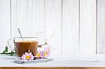 Coffee Cup And A Mobile Phone With Flowers On The White Wooden Table Stock Photo