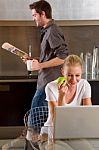 Couple At Kitchen Using Laptop Stock Photo