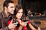 Couple Enjoying Wine Near Fireplace Stock Photo