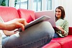 Couple Using Technologies On Red Sofa Stock Photo