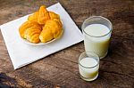 Croissant On Dish With Milk On Old Wooden Table Stock Photo