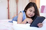 Cute Girl Are Playing A Tablet On The Bed Stock Photo