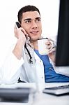 Doctor Talking Over Telephone And Having Coffee Stock Photo