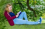 Dutch Girl Lying Reading Book In Green Tree Stock Photo