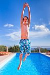Dutch Teenage Boy Jumping High Above Blue Swimming Pool Stock Photo