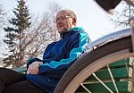 Eldely Man Sitting On A Bench Near His Bicycle In A City Park Stock Photo