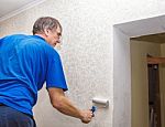 Elderly Man Smoothing The Wallpaper With A Roller Stock Photo