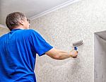 Elderly Man Smoothing The Wallpaper With A Roller Stock Photo