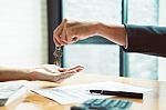 Estate Agent Giving House Keys To Man And Sign Agreement In Offi Stock Photo