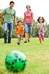 Family Playing Football In The Park Stock Photo