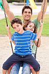 Father And Children Enjoying Swing Ride Stock Photo