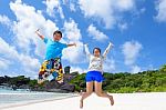 Father And Daughter Jumping On Beach At Thailand Stock Photo