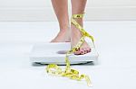 Female Feet Standing On A Bathroom Scales And A Tape Measure Stock Photo