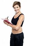 Female Gym Instructor Writing Diet Chart Stock Photo