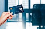 Female  Hand Holding Credit Card Against Business Office Backgro Stock Photo