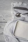 Feta With Cutlery And Napkin On The White Wooden Table Vertical Stock Photo