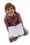 Front View Of Boy Sitting On Books And Reading Book Stock Photo