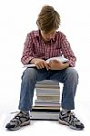 Front View Of Boy Sitting On Books On White Background Stock Photo