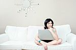 Girl On White Sofa With Laptop Stock Photo