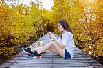 Girl Sitting Alone And Hand Holding Camera On A The Wooden Bridge In Autumn Stock Photo