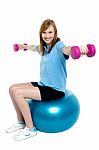 Girl Sitting On Pilates Ball And Doing Dumbbells Stock Photo