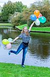 Girl Standing At Pond With Colored Balloons Stock Photo