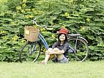 Girl With A Bicycle Rests On A Grass Stock Photo