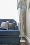 Grey Pillows On Classic Blue Sofa With Floor Lamp Stock Photo