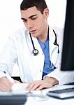 Handsome Doctor Making Notes From The Computer Stock Photo