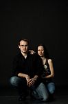 Handsome Young Couple Posing Sitting In Studio Stock Photo