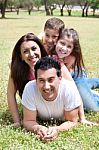 Happy Family Lying In The Grass Field Stock Photo