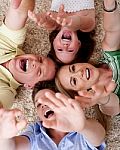 Happy Family Of Four Lying On The Carpet Stock Photo