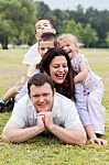 Happy Family Piled Up  On The Park And Looking At You Stock Photo