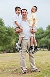 Happy Father Carrying His Two Son In His Hands Stock Photo