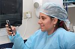 Happy Female Surgeon Reading Message At Mobile Phone Stock Photo