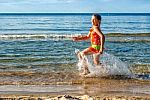 Happy Little Girl Making Splashes On The Beach Stock Photo