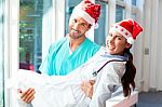 Happy Surgeon Carrying Female Doctor During Christmas Stock Photo