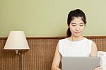 Happy Young Asian Woman Working With Laptop In Bedroom Stock Photo
