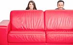 Happy Young Couple Hiding Behind Red Sofa Stock Photo