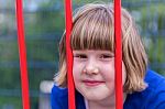 Head Of Young Girl Behind Red Bars Stock Photo