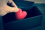 Human Hand Holding Or Putting A Red Heart-shaped In A Black Gift Stock Photo