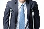 Injured Businessman With Crutches, Insurance Concept Stock Photo