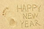 Inscription 'happy New Year' And Human Footprint In The Sand On Stock Photo
