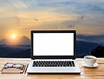 Laptop And Coffee On Workspace And Mountain At Sunset Background Stock Photo