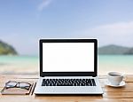 Laptop Computer And Coffee On Wood Workspace And The Beach Background Stock Photo