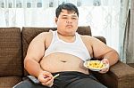 Lazy Overweight Male Sitting With Fast Food Stock Photo