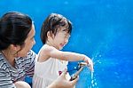 Little Asian Girl And Mother Play With Water Hose Stock Photo