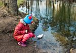 Little Girl Let A Paper Boat On The River Outside Stock Photo